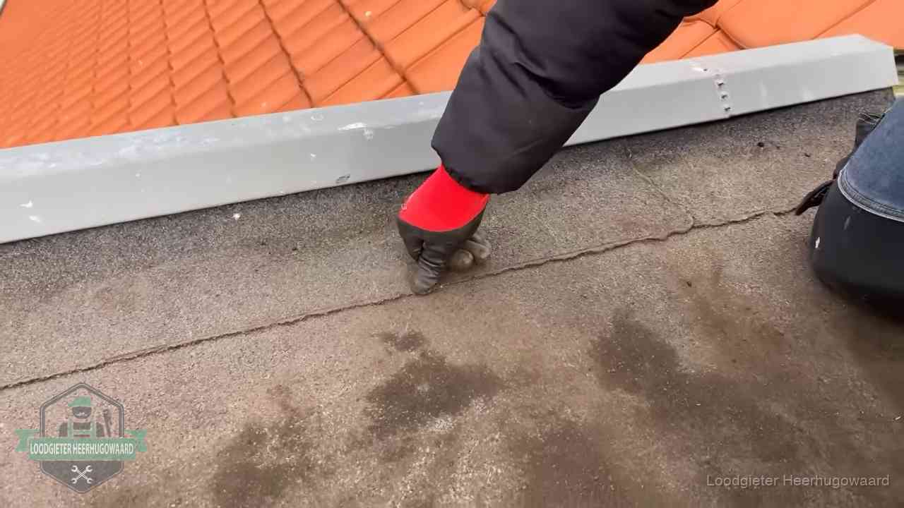 Lekkage bij de naad van een plat dak in Heerhugowaard Vakman wijst een naad met vochtplekken aan op een bitumen plat dak in Heerhugowaard