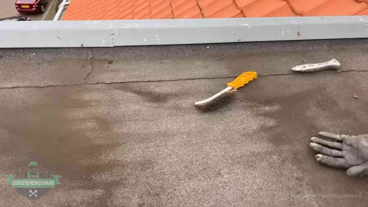 Kosten van daklekkage-reparatie in Heerhugowaard Dakdekker bereidt een bitumen plat dak voor op reparatie bij de daktrim in Heerhugowaard