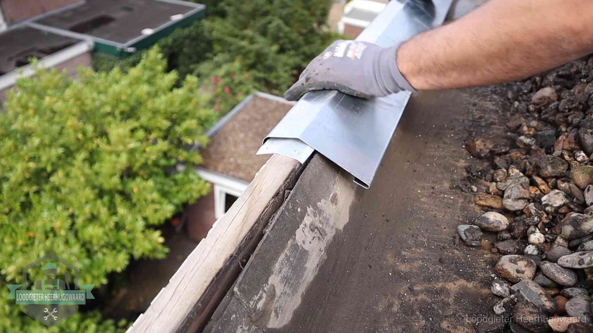 Daklekkage per wijk in Heerhugowaard Dakdekker plaatst een zinken deklijst op een dakrand met uitzicht over een woonwijk in Heerhugowaard