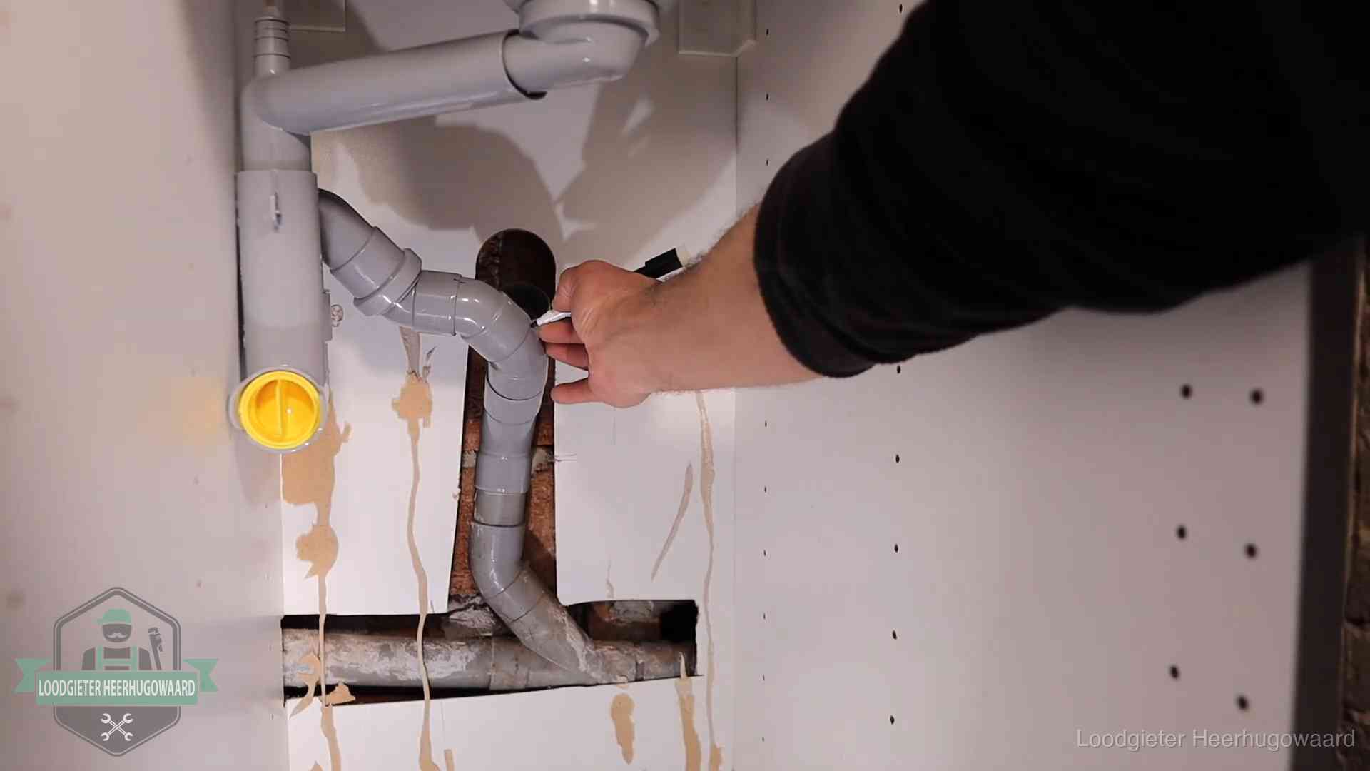 Loodgieter voor verhuurders en bedrijven in Heerhugowaard Loodgieter markeert een pvc-afvoerbuis onder een gootsteen in Heerhugowaard