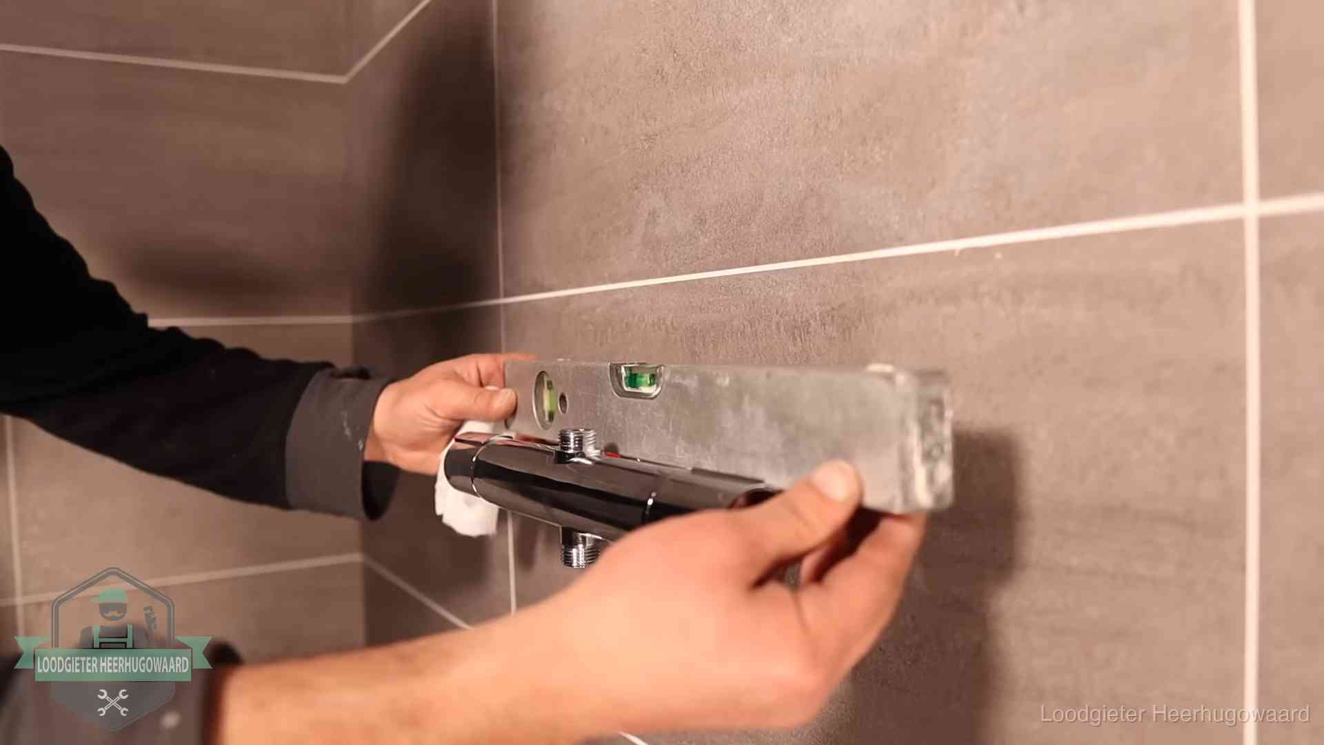 Loodgietersbedrijf voor sanitair in Heerhugowaard Loodgieter lijnt een douchekraan uit met een waterpas in een woning in Heerhugowaard