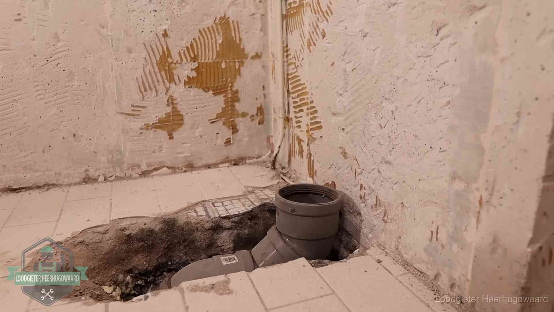 Verzakt riool herstellen in Heerhugowaard Opengebroken vloer met een nieuwe pvc-rioolbocht in een gegraven sleuf in Heerhugowaard