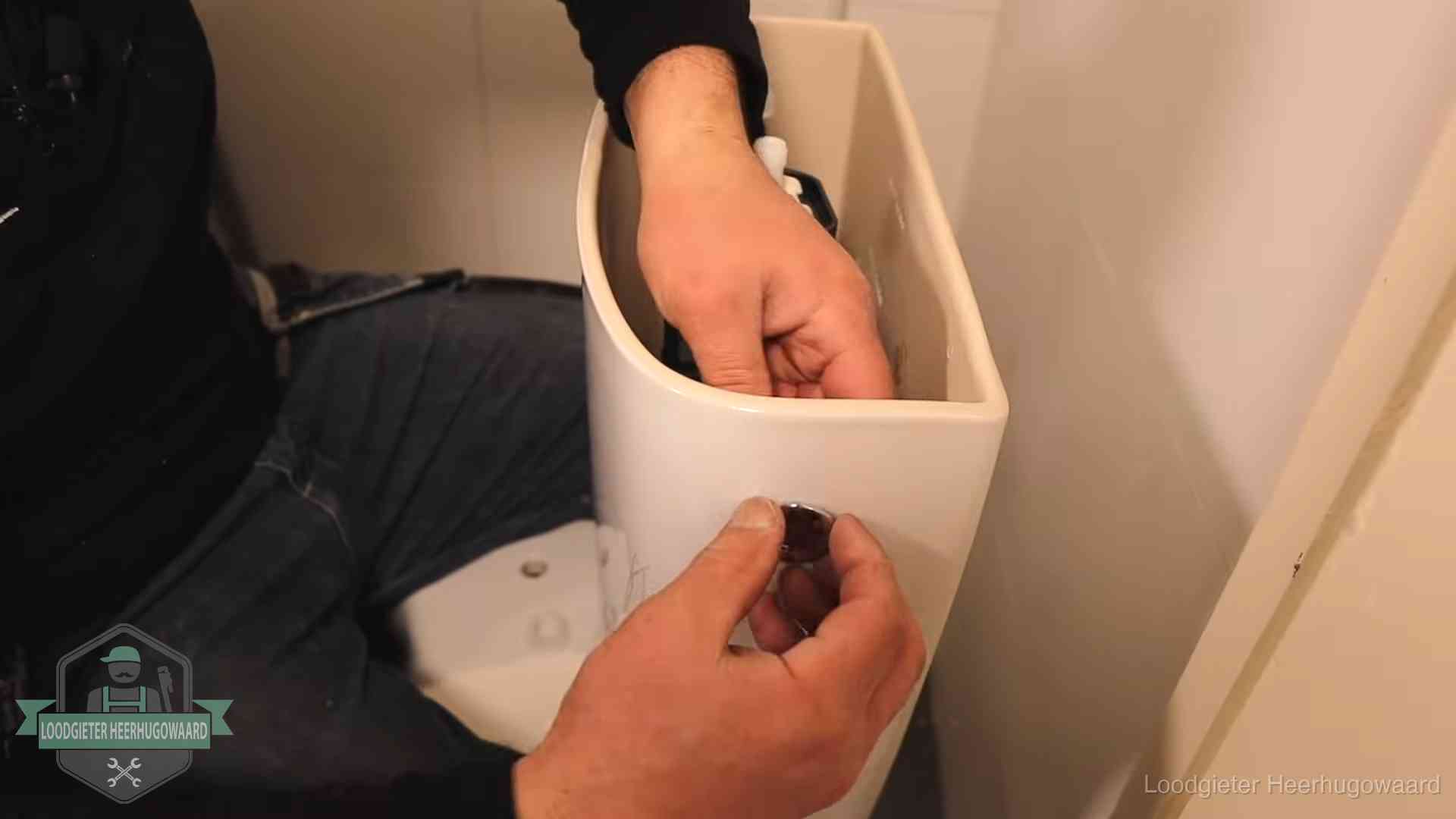 Drukknop van een duoblok-stortbak wordt gemonteerd bij een toilet in Heerhugowaard
